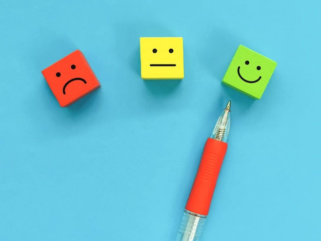 Photo credit score concept with emotion icons on colorful wooden cubes with a pen.