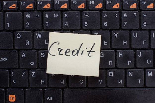 Credit words written on note paper. Note on the black keyboard.