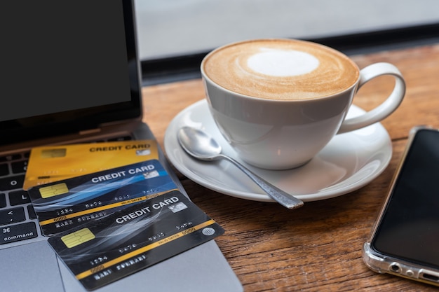 Creditcard van laptopcomputer, smartphone en koffiekopje op houten achtergrond, Online bankieren Concept