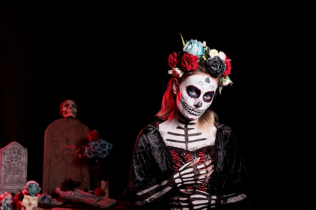 Raccapricciante dea della morte con trucco da festival e costume di halloween per celebrare la festa messicana di dios de los muertos. donna spettrale come santa muerte con corona di fiori, giorno dei morti.