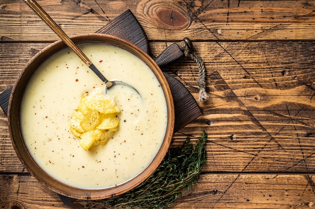 Crème aardappelsoep met chips in houten plaat. houten achtergrond. Bovenaanzicht. Ruimte kopiëren.