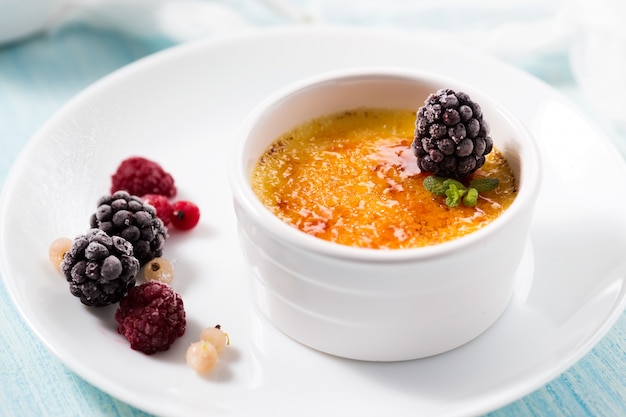 Creme brulee decorated blackberry on a white plate