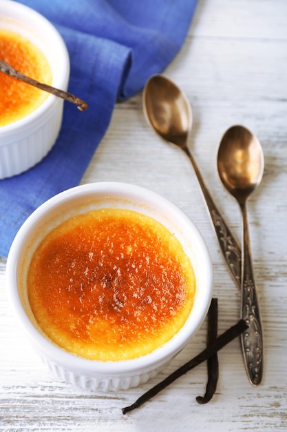 Creme brulee dessert on napkin on color wooden background