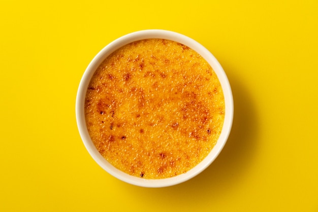 Creme brulee in ramekin geïsoleerd op helder geel