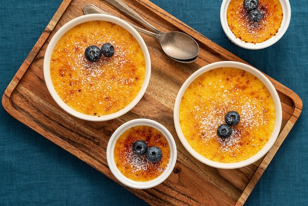 Crème brûlée in un sacco di ramekin sul vassoio in legno