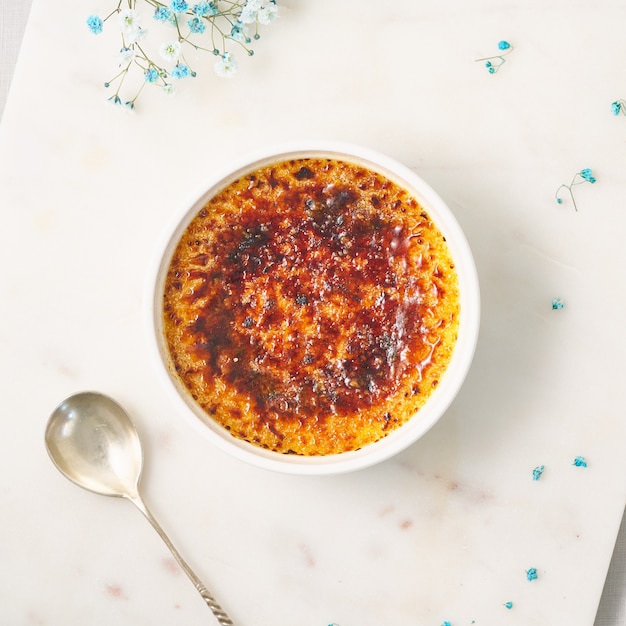 Creme brulee traditional french vanilla cream dessert burned cream with spoon in ramekin