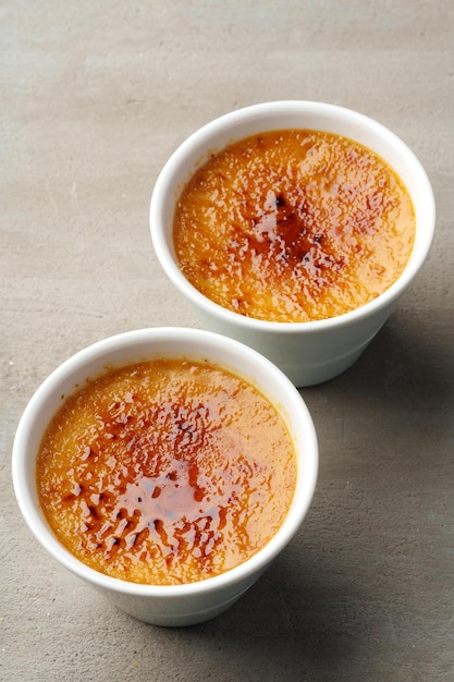 Creme brulee with caramel in two white bowls on gray background