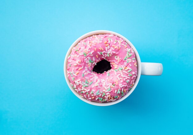 Crème donut in een kopje op blauwe achtergrond. Boven weergave