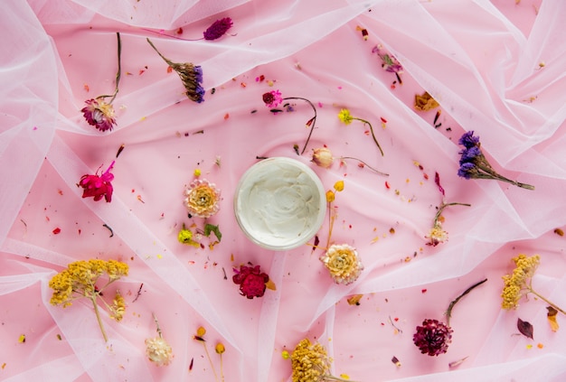 Crème met droge bloemen op roze tule. Natuurlijk licht