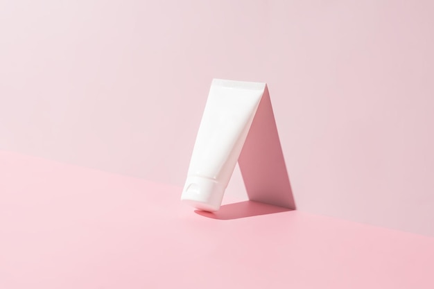 Crème tube op heldere zonnige roze achtergrond Cosmetisch huidverzorgingsproduct blanco plastic pakket Witte merkloze lotion balsem handcrème mockup Zonnebrandcrème fles