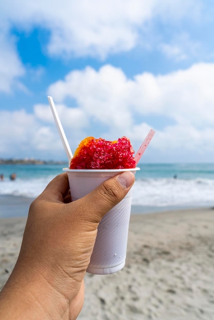 cremolada met aardbeiensmaak in een wit glas op het strand.