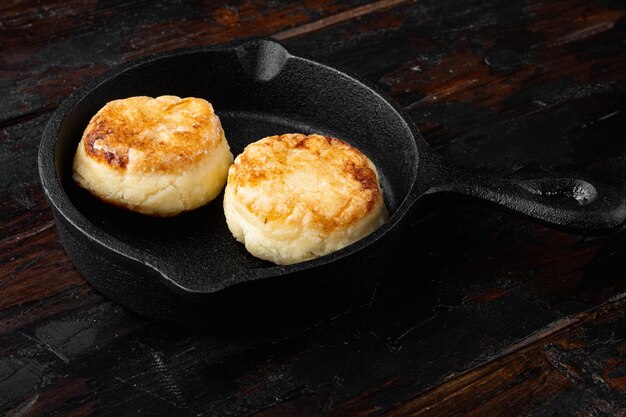 Crepe Fritters of cottage cheese  on cast iron frying pan skillet on cast iron frying pan skillet, on black wooden table background