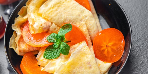 Crêpe persimmon dunne pannenkoeken fruit ontbijt zoet dessert gezonde maaltijd eten snack op tafel