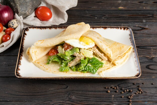 サラダと卵のクレープ。目玉焼き、鶏肉の切り身、野菜、サラダを添えたパンケーキの朝食またはランチのホットメインコース