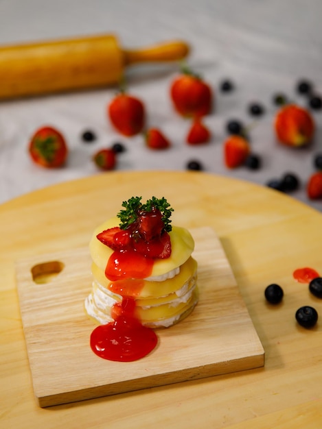Crêpecake met aardbeiensaus heerlijk versierd met verse aardbeien op een houten bord, voor verjaardag, Valentijnsdag en feest