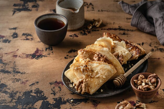 Foto crêpes of dunne pannenkoeken met honing en noten op een bruine plaat op een houten achtergrond heerlijke crêpes