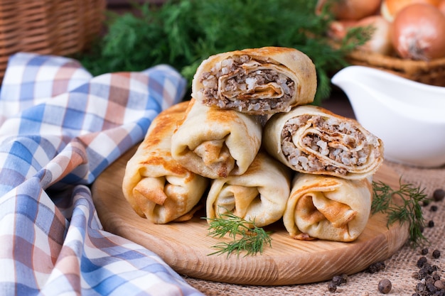 Crepes stuffed with minced meat and rice on a cutting board