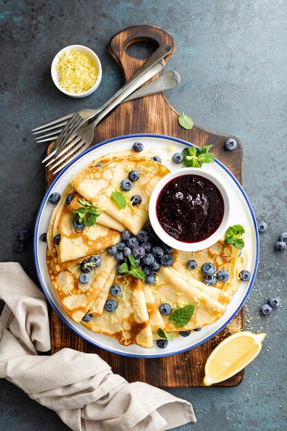 Crepes thin pancakes with blueberry jam and fresh berries with lemon zest