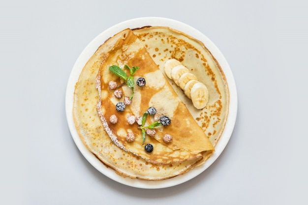 Crepes, thin russian pancakes on white plate.