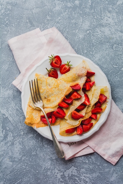 блины со свежей клубникой и медом на сером фоне бетона. Вид сверху.