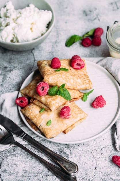 Crepes with homemade cottage cheese, raspberries a gray plate