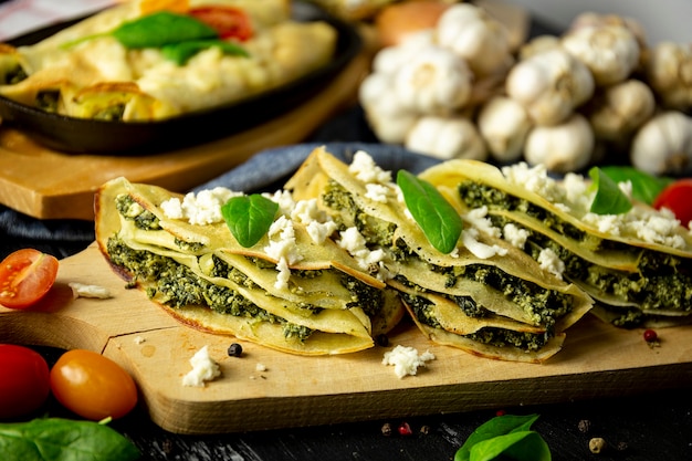 Crepes with spinach on the cutting board, black table