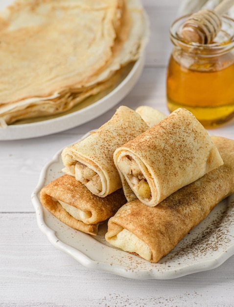 Crepes with stuffing on a plate There is a towel and a jar of honey nearby