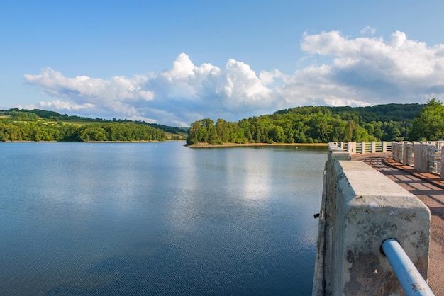 Photo crescent lake of a dam with road crossing water and forestcovered hill in the morvan in france