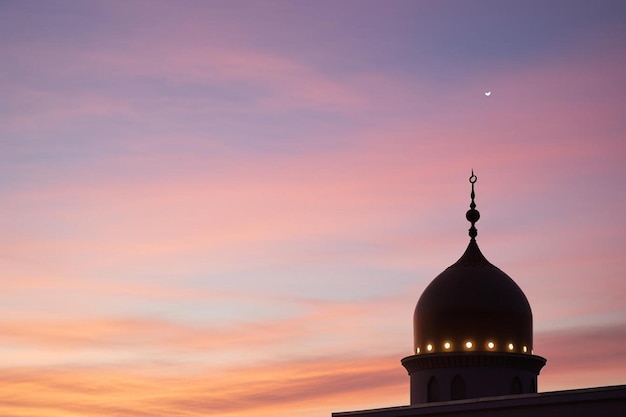 Crescent moon and mosque dome at dusk