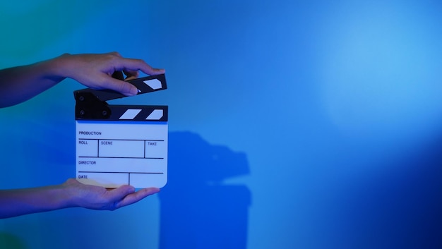 Crew hand holding plastic and wooden film slate board against camera