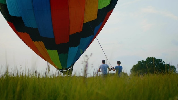 Crew inflate a colored hot air balloon at summer field