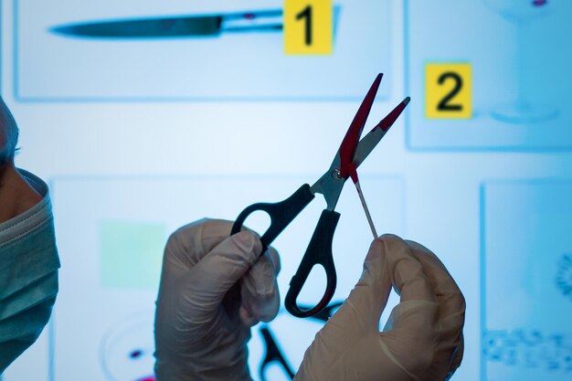 Photo a crime lab technician holds scissors and takes a blood sample in the crime lab against