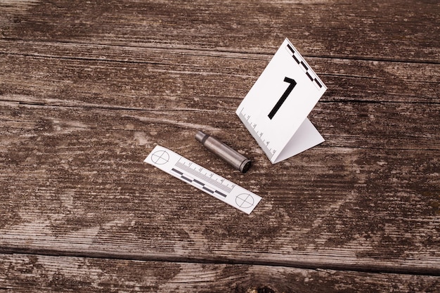 Crime scene investigation collecting bullet shell on the wooden background xAxA