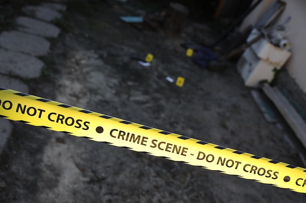 Crime scene tape for covering the area cordon Yellow tape with blurred forensic law enforcement background in cinematic tone