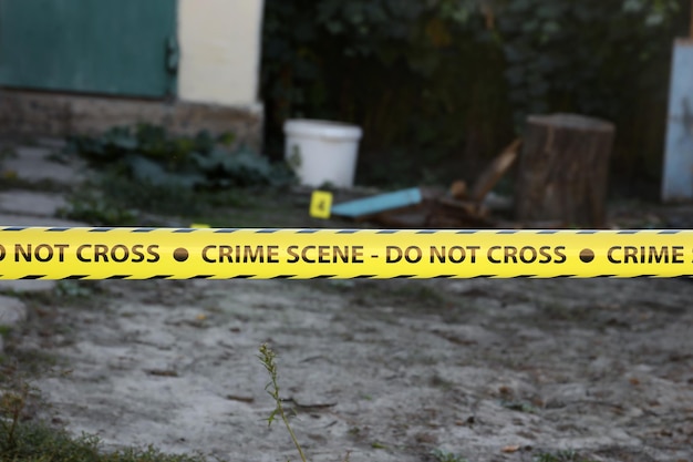 Crime scene tape for covering the area cordon yellow tape with\
blurred forensic law enforcement background in cinematic tone