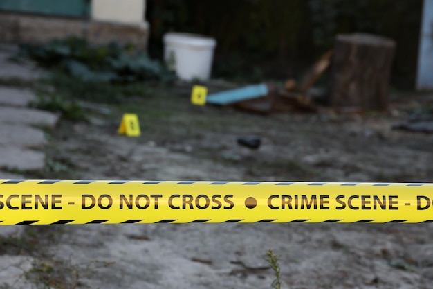 Crime scene tape for covering the area cordon yellow tape with\
blurred forensic law enforcement background in cinematic tone