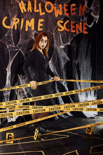 Foto muro della scena del crimine. ritratto di donna che è sulla festa di halloween tematica in trucco e costume spaventosi.