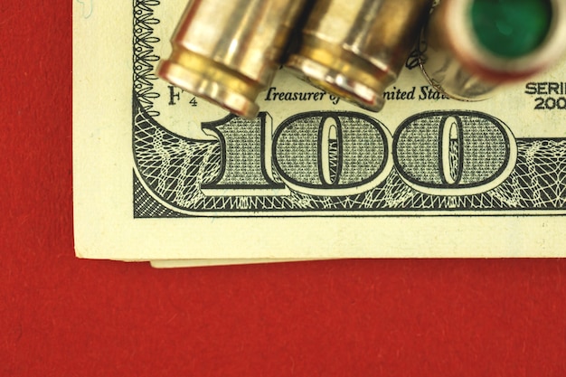 Foto concetto di denaro criminale e sanguinoso con banconote da cento dollari e munizioni, proiettile per pistola, foto di vista ravvicinata