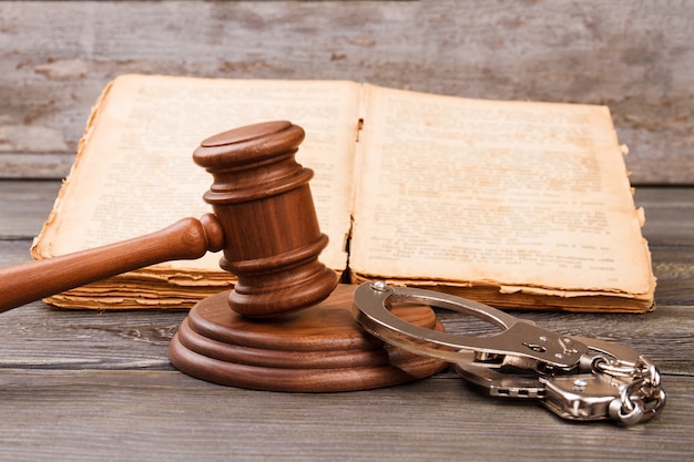 Criminal court concept. Gavel with handcuffs and old worn book with laws.