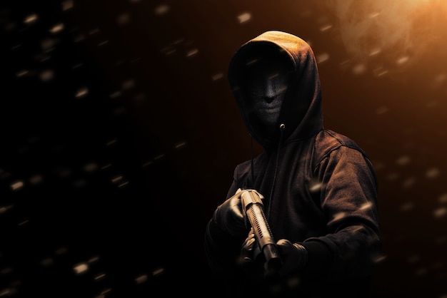 Criminal man in a hidden mask holding the shotgun with dramatic background