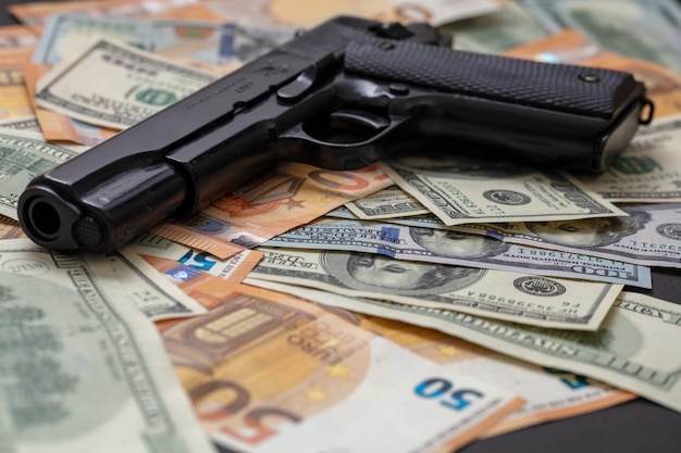 Criminal money Pistol on dollar and euro banknotes background Mafia and corruption concept