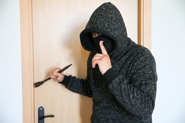 ドアの近くにバールを持った犯罪者。強盗が家に侵入。