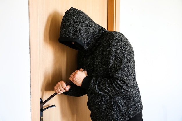 Фото Преступник с ломом у дверей. грабитель ворвался в дом.
