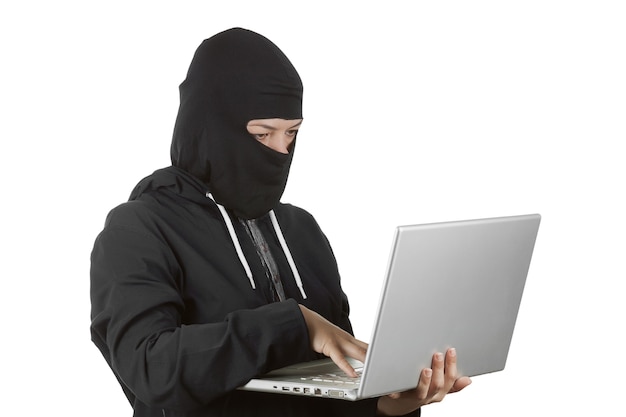 흰색 바탕에 노트북을 사용하여 검은 옷과 발라클라바에 후드를 입은 범죄 여성 해커