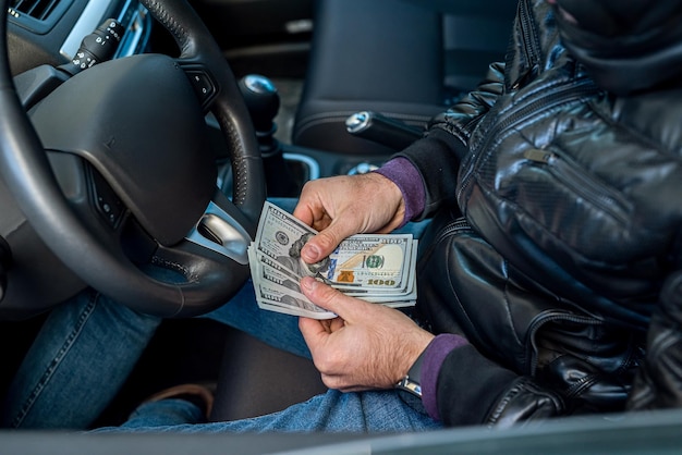 Criminele man met een grote som dollarbiljetten in de auto