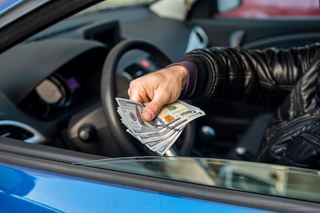 Criminele man met een grote som dollarbiljetten in de auto