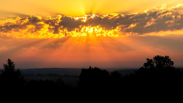 Crimson sunrise sunset bright rays of the sun breaking through the clouds