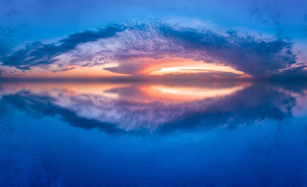 The crimson sunset is reflected in the water of the lake, a beautiful morning summer landscape.