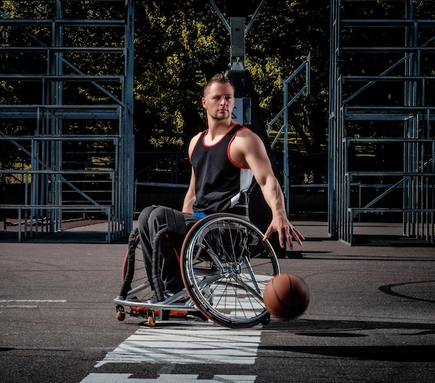 Cripple basketball player in a wheelchair plays on an open gaming ground.