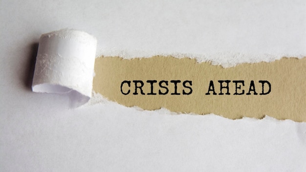 Crisis ahead words text on grey paper on torn paper background